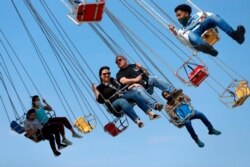 FILE - People enjoy their time in a wave swinger, May 14, 2021, at Chicago's Navy Pier. The U.S. Centers for Disease Control and Prevention has eased its guidelines, saying fully vaccinated people can resume activities without wearing masks.