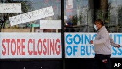 FILE - A man looks at signs of a closed store due to COVID-19 in Niles, Ill., May 21, 2020.