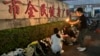 A woman lights a candle near flowers placed outside the Zhuhai People's Fitness Plaza where a man deliberately rammed his car into people exercising at the sports center, in Zhuhai in southern China's Guangdong province, Nov. 12, 2024.