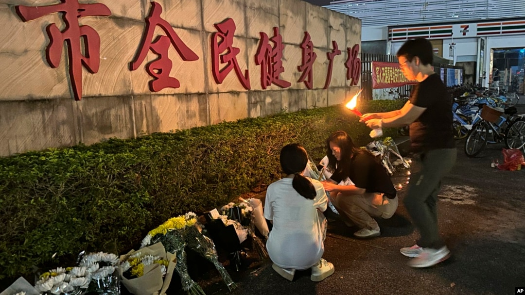 A woman lights a candle near flowers placed outside the Zhuhai People's Fitness Plaza where a man deliberately rammed his car into people exercising at the sports center, in Zhuhai in southern China's Guangdong province, Nov. 12, 2024.