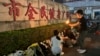 A woman lights a candle near flowers placed outside the Zhuhai People's Fitness Plaza where a man deliberately rammed his car into people exercising at the sports center, in Zhuhai in southern China's Guangdong province, Nov. 12, 2024.