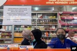 Karyawan menunggu pelanggan di loket yang menampilkan pemberitahuan penghentian sementara penjualan sirup obat di apotek di Jakarta, Kamis, 20 Oktober 2022. (AP/Tatan Syuflana)