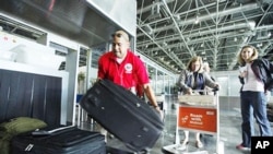 U.S. embassy staff member puts luggage into an X-ray machine as U.S. citizens are evacuated at Cairo airport, Egypt, February 2, 2011