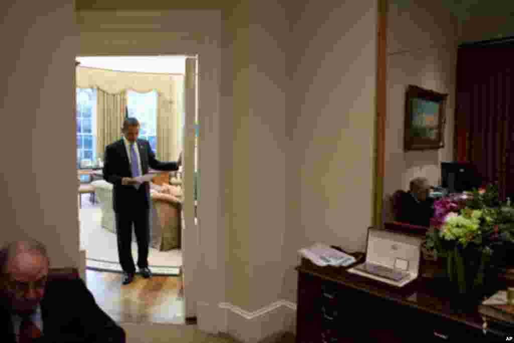 奥巴马总统打开椭圆形办公室的门与等候在那里的白宫官员交谈(9月1日)