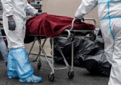 Personas en trajes de protección transportan en una camilla el cuerpo de una persona fallecida, afuera de una funeraria en Brooklyn el 30 de abril de 2020 en la ciudad de Nueva York.