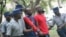 FILE - Activist Itai Dzamara, center left in red and blue, is detained by police in Zimbabwe in this undated photo and has been missing since 2015.