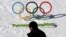FILE - A man walks by the Olympic rings with a sign of 2018 Pyeongchang Olympic Winter Games, in Pyeongchang, South Korea, Feb. 3, 2017. 