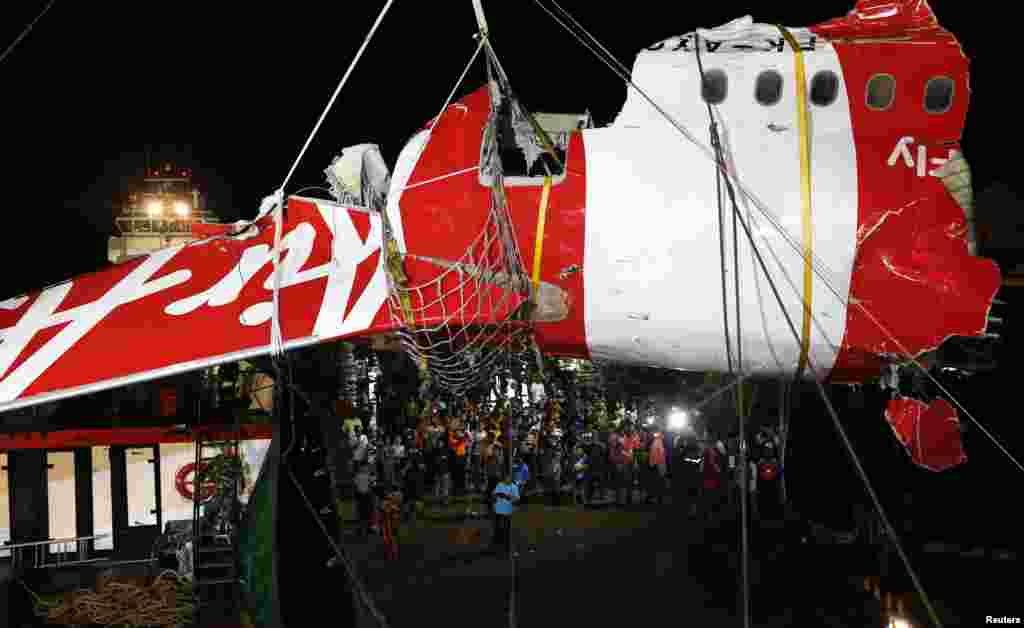 A section of the tail of AirAsia QZ8501 passenger plane is lifted off a ship and onto the back of a truck, the day after it was lifted from the seabed, in Kumai Port, near Pangkalan Bun, central Kalimantan, Jan. 11, 2015.
