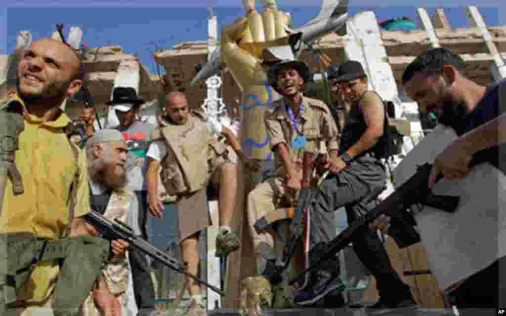 Rebel fighters gesture as they stamp on a part of a statue of Moammar Gadhafi inside the main compound in Bab Al-Aziziya in Tripoli, Libya,