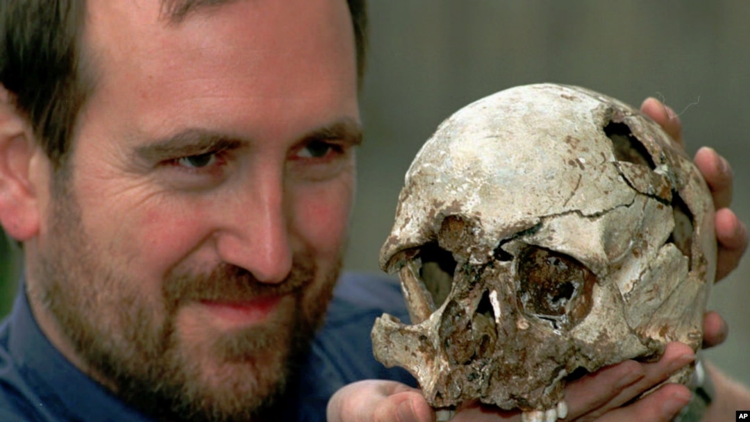 FILE - Dr. Chris Stringer the principal researcher of human origin at the Natural History Museum in London with the skull of Cheddar Man, a 9,000-year-old skeleton, March 7, 1997. (AP Photo/Michael Stephens)