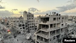 FILE - Palestinians walk at the site of Israeli strikes on houses, in Jabalia refugee camp in the northern Gaza Strip November, 21, 2023. 