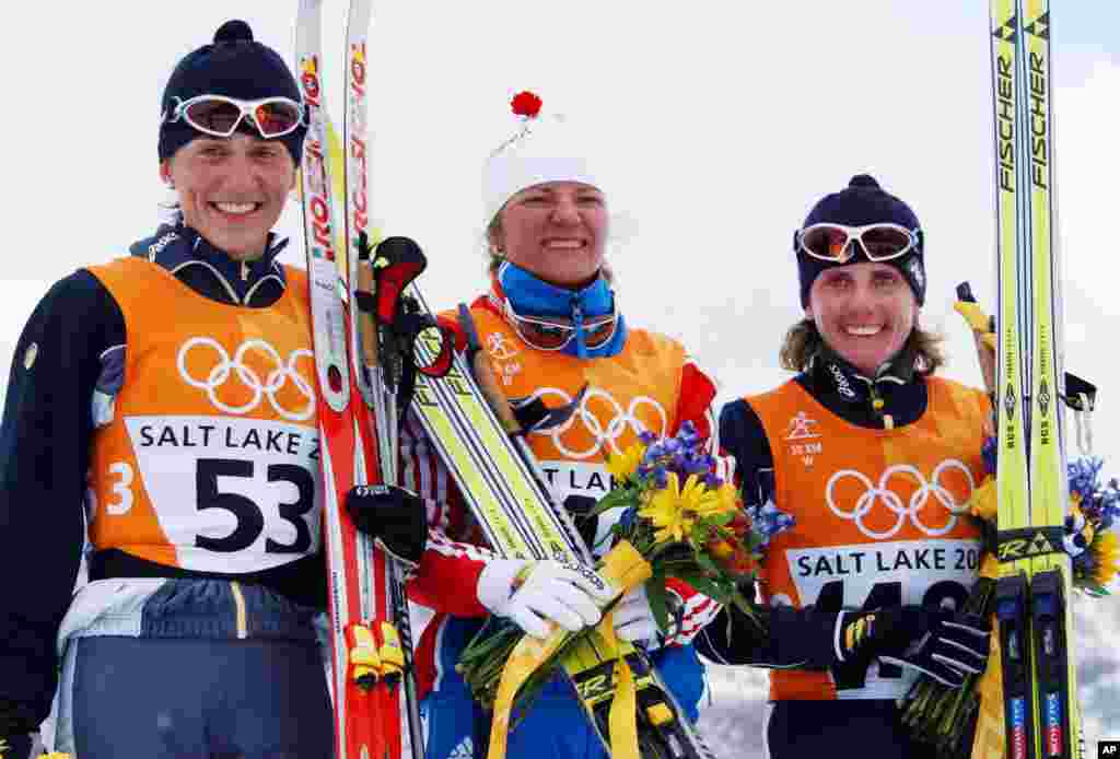 Le médaillé d'argent de l'Italie Gabriella Paruzzi, à gauche, le médaillé d'or de la Russie Larissa Lazutina, centre et le médaillé de bronze en Italie Stefania Belmondo célébrent elur sacre sur le podium lors de la cérémonie de fleurs de 30 km course classique de cross-country des femmes.