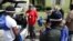 Morris Copeland, of the Strategic Urban Response to Guideline Education group, center, passes out kits to be distributed to residents in COVID-19 hot spots, July 1, 2020, in the Liberty City neighborhood of Miami.