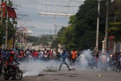 Protesters turn and run as police began to fire tear gas as they gather in Port-au-Prince, Haiti, Sept. 30, 2019.