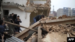 FILE - A woman reacts after trying to protect her home as demolition workers move in, in Yangji village, Guangzhou, China, March 21, 2012. Yangji was scheduled for redevelopment and gradually demolished, making way for modern housing.