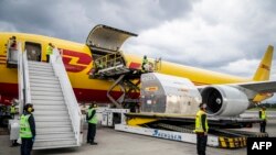 Petugas bandara membongkar kontainer berpendingin yang menampung 50.000 dosis vaksin COVID-19 produksi Pfizer, di Bandara Internasional El Dorado, Bogota, 15 Februari 2021. (Foto: Efrain HERRERA / Colombian Presidency / AFP) 