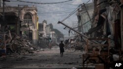 FILE - At top, Jan. 20, 2010, a street devastated by the earthquake that struck one week earlier in Port-au-Prince; below, Jan. 10, 2015, the same location. 