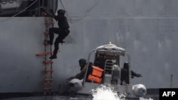 FILE - A Nigerian special guard climbs a ladder as he boards a vessel during a joint exercise between Nigerian and Moroccan naval personnel as part of a multinational maritime exercise off the coast of Lagos, March 20, 2019.