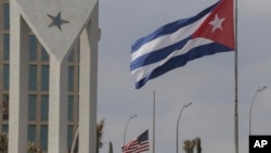 Bandeiras cubana e americana esvoaçam ao vento no exterior da embaixada americana em Havana, Cuba, 14 de janeiro de 2025.