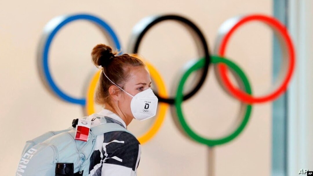 Un atleta alemana, con mascarilla, pasa junto a la exhibición de anillos olímpicos a su llegada al aeropuerto de Haneda en Tokio, el 1 de julio de 2021.