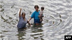 Người dân Thái Lan lội qua nước lũ ngập tới ngang hông ở Bangkok, ngày 30/10/2011