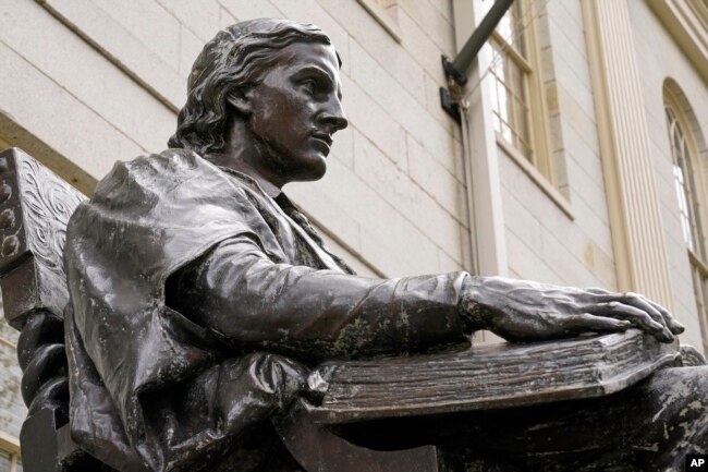 The statue of John Harvard, founder of Harvard College, is seen at Harvard Yard, Wednesday, April 27, 2022, on the campus of Harvard University in Cambridge, Mass. In Harvard's pledge to atone for its ties to slavery, it identified dozens of people who were enslaved by the university's first leaders and faculty members. (AP Photo/Charles Krupa)