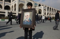 A boy carries a portrait of Iranian Revolutionary Guard Gen. Qassem Soleimani, who was killed in the U.S. airstrike in Iraq, prior to the Friday prayers in Tehran, Iran, Friday Jan. 3, 2020. Iran has vowed "harsh retaliation" for the U.S. airstrike…