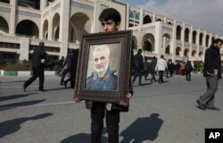 A boy carries a portrait of Iranian Revolutionary Guard Gen. Qassem Soleimani, who was killed in the U.S. airstrike in Iraq, prior to the Friday prayers in Tehran, Iran, Friday Jan. 3, 2020. Iran has vowed "harsh retaliation" for the U.S. airstrike…