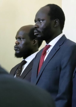 Kerbino Wol, a businessman, and Peter Biar Ajak, the South Sudan country director for the London School of Economics International Growth Center based in Britain, stand in the dock inside the courtroom in Juba.