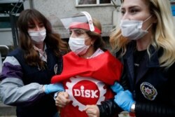 FILE - Turkish police officers, wearing face masks to protect against the coronavirus, arrest a demonstrator during May Day protests against the government lockdown, in Istanbul, May 1, 2020.