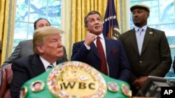 El presidente Donald Trump, izquierda, y el campeón de peso pesado, Lennox Lewis, a la derecha, observan a Sylvester Stallone gesticular en la Oficina Oval de la Casa Blanca en Washington, el jueves 24 de mayo de 2018, donde Trump concedió un perdón póstumo a Jack Johnson, primer campeón negro de peso pesado.