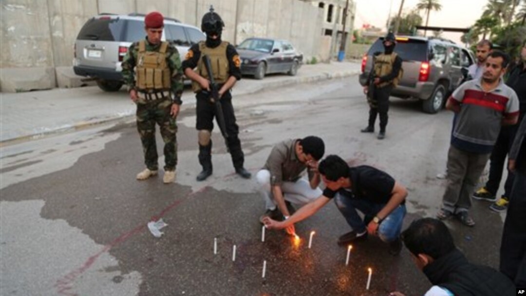 Pasukan keamanan berjaga-jaga sementara para jurnalis Irak menyalakan lilin di tempat kepala biro Radio Free Iraq di Baghdad, Irak (22/3). (AP/Karim Kadim)