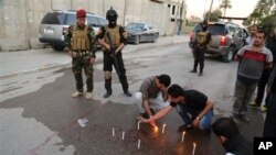 Soldados iraquís observan mientras periodistas colocan velas en el lugar en que murió el jefe de la oficina de Radio Irak libre en Bagdad.