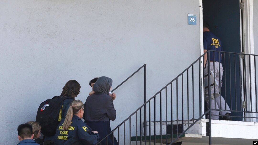 Seorang perempuan menggendong anak sedang dikawal oleh para petugas ke sebuah apartemen menyusul penanggapan pengungsi Irak berusia 45 tahun, Rabu, 15 Agustus, di Sacramento, California.