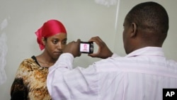 A detained Somali woman has her photograph taken before being fingerprinted and screened at the Kasarani sports stadium, which has been converted into a detention facility to hold those arrested during recent security crackdowns, near Nairobi in Kenya, April 9, 2014.