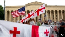 An activist wearing a face mask to protect against coronavirus holds the Georgian flag during a rally in Tbilisi, Georgia, June 20, 2020. 
