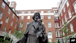 FILE - A Jesuit statue is seen in front of Freedom Hall, formerly named Mulledy Hall, on the Georgetown University campus in Washington, September 2016. The U.S.-based branch of the Jesuits has unveiled ambitious plans for a “truth and reconciliation” ini