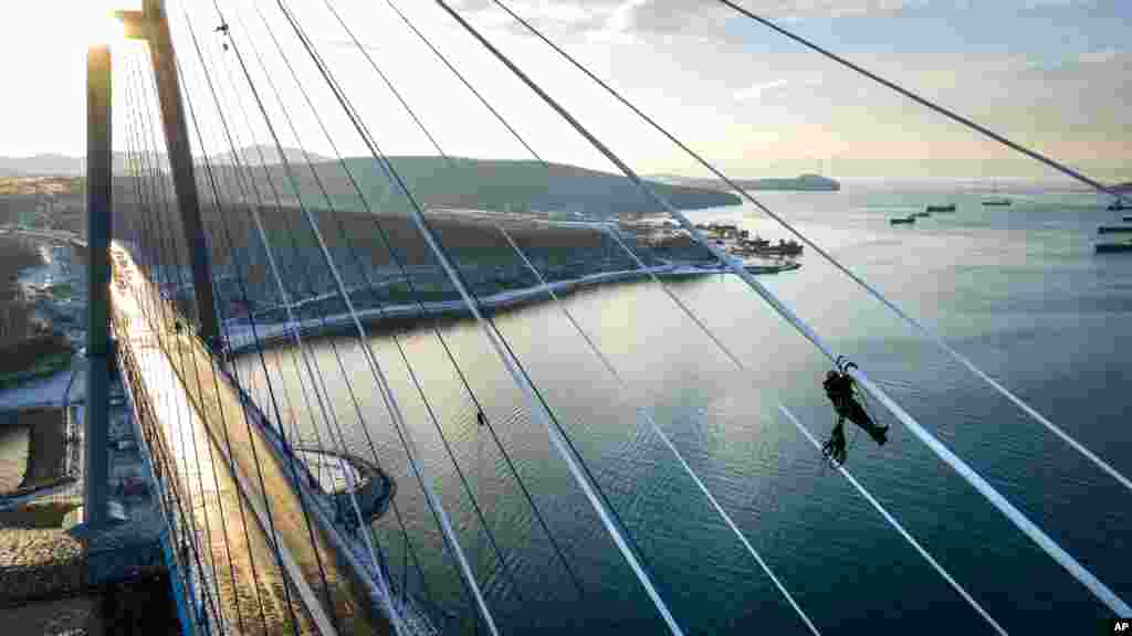 Industrial climbers remove ice from the cables of the Russky Bridge across the Eastern Bosphorus Strait in Vladivostok, Russia. The bridge was temporarily closed after an ice storm.