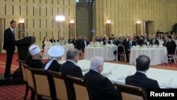 Syria's President Bashar al-Assad (L) delivers a speech while attending an Iftar, or breaking fast session, during the Muslim month of Ramadan in Damascus, Aug. 4, 2013.