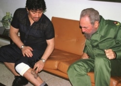 FILE - Argentine soccer legend Diego Maradona, then in Cuba undergoing rehabilitation for cocaine abuse, shows Cuban President Fidel Castro a tattoo on his leg, inside Revolution Palace in Havana, Oct. 29, 2001.