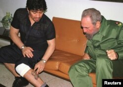 FILE - Argentine soccer legend Diego Maradona, then in Cuba undergoing rehabilitation for cocaine abuse, shows Cuban President Fidel Castro a tattoo on his leg, inside Revolution Palace in Havana, Oct. 29, 2001.