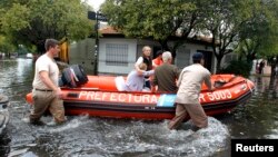 Nhân viên cứu hộ Argentina sơ tán 2 phụ nữ sau khi mưa làm ngập lụt phần lớn thành phố La Plata, ngày 3/4/2013. 