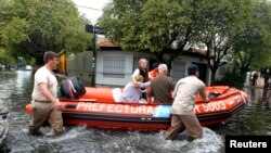 Miembros de la Guardia Costera argentina evacúan a dos mujeres en La Plata, capital de la provincia de Buenos Aires. El Papa ha hecho un llamado a la solidaridad para con sus compatriotas.