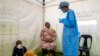 Une femme avec son enfant vont se faire tester pour le coronavirus au nord de Johannesburg, Afriquique du Sud le 8 mai 2020.