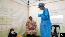 A woman with her child listens as a heath worker explains the process of collecting a sample for coronavirus testing, during the screening and testing campaign aimed to combat the spread of COVID-19 Diepsloot, Johannesburg, South Africa, May 8, 2020.