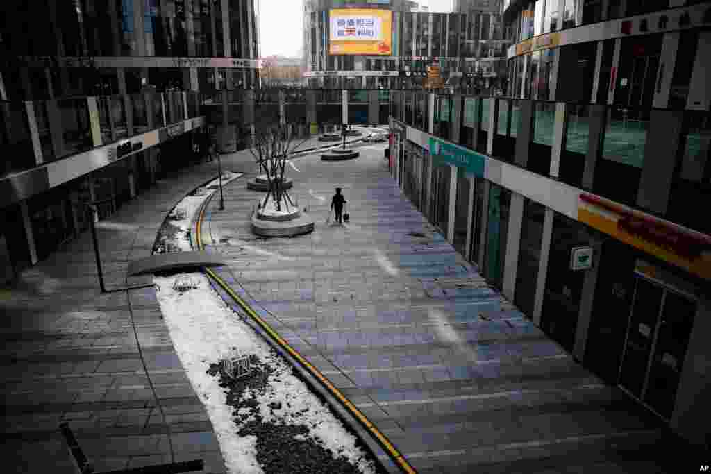 A cleaner walks through a deserted compound of a commercial office building in Beijing, China. China reported a rise in new virus cases, possibly denting optimism that its disease control measures like isolating major cities might be working.