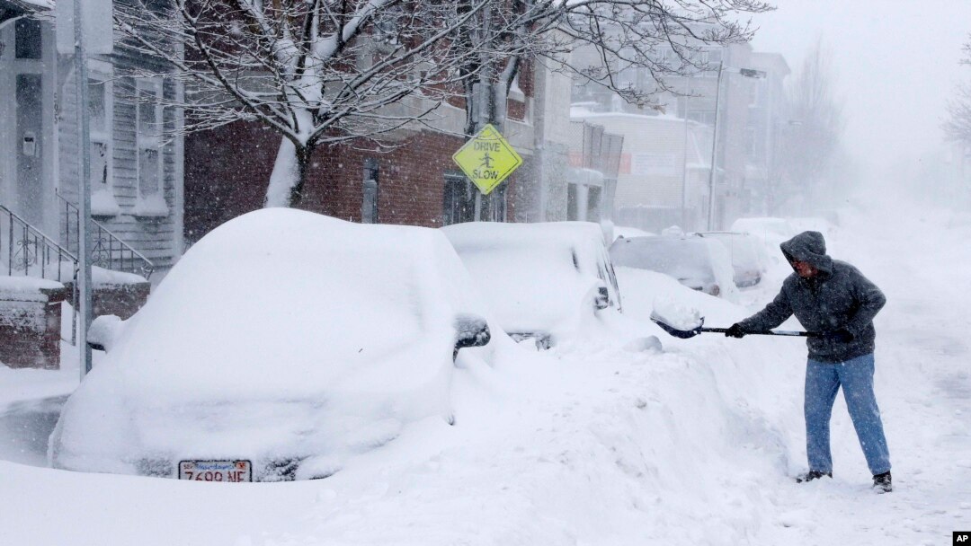 Warga mengeruk salju yang menimbun mobil di kota Boston, Sabtu (9/2), akibat badai salju. (AP/Gene J. Puskar)