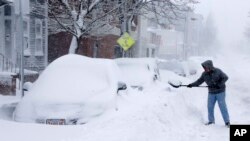 Warga mengeruk salju yang menimbun mobil di kota Boston, Sabtu (9/2), akibat badai salju. (AP/Gene J. Puskar)