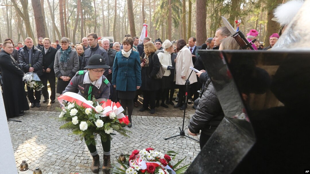 A girl scout lays a wreath at the central monument of a cemetery near the village of Jagiella, in southern Poland, Thursday, March 17, 2016 during ceremonies remembering the Ulma family and eight Jews they were sheltering during Holocaust, all of whom wer