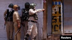 An Indian policeman uses a slingshot to hurl stones towards protesters during a clash on the anniversary of the killing by Indian forces of Burhan Wani, a commander of the Hizbul Mujahideen militant group, in downtown Srinagar, July 8, 2017.